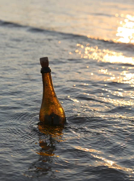 bottle with the message in the ocean at sunset