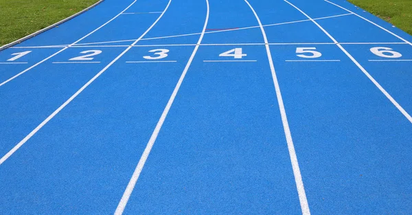 lanes of a blue athletic track with numbers one two three four five six