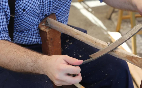 carpenter uses an old planer to plan the wood of a stick