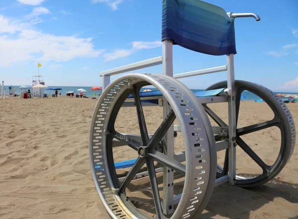 夏の観光村の砂浜のビーチでも移動する変更された車輪を持つ独創的な車椅子 — ストック写真