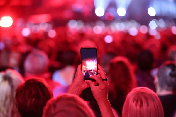 woman with smartphone during a live concert with a lot of people