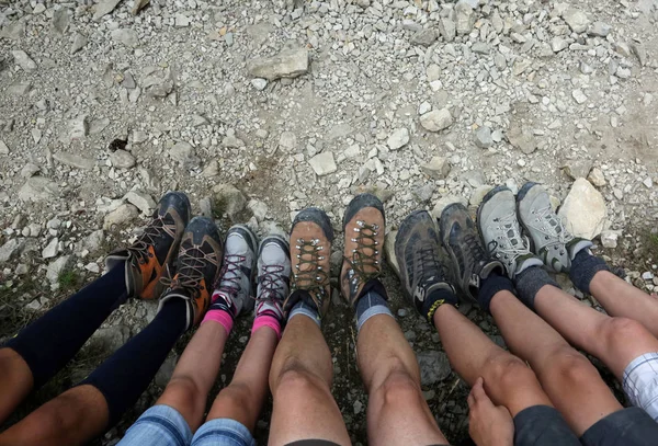 ten boots of the tired family of five walkers while they rest after the hike in the mountains