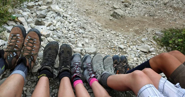 Ten legs of the five-person family while resting after the hike in the mountains with mountain boots