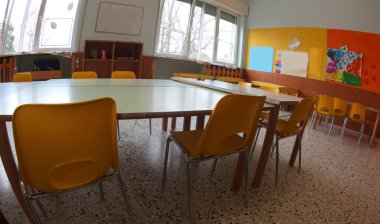 Bir Kingergarten sarı sandalye ve küçük tablolar ile geniş bir sınıf içinde