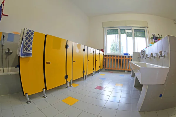 セラミック シンクと子供たちと明るい窓なしの黄色いドアの清潔なトイレ — ストック写真