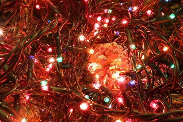 golden pine cone and colored led lights of christmas tree