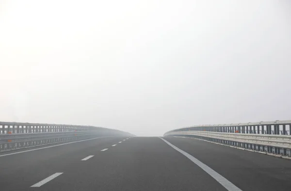 Autobahn bei dichtem gefährlichen Nebel ohne Autos während eines Tages in w — Stockfoto
