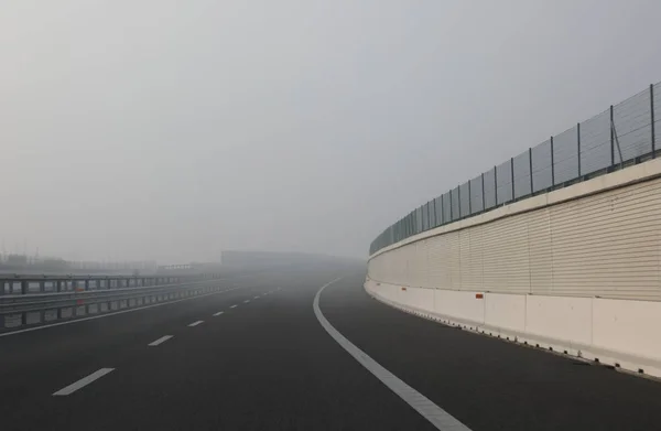 Плотный очень опасный туман рядом с изгибом шоссе — стоковое фото