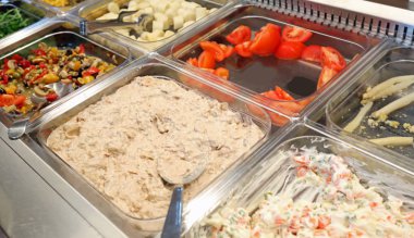 şirket kantinde pişmiş ve pişmemiş yiyecek birçok tepsiler