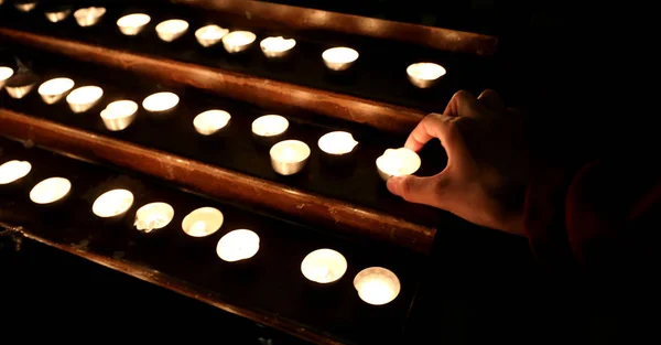 Mão com muitas velas com a chama no lugar de culto du — Fotografia de Stock