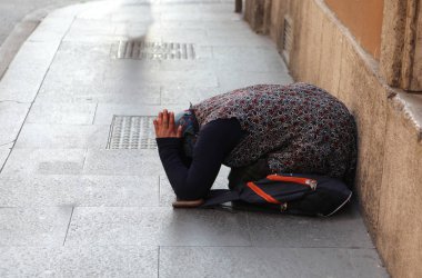 İle yere diz çökmüş sadaka isteyen yaşlı Çingene Kadın 