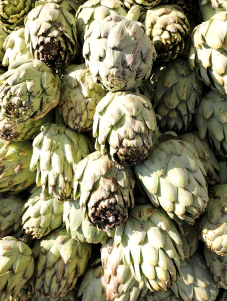 Background many large artichokes for sale at the greengrocer's s — Stock Photo, Image