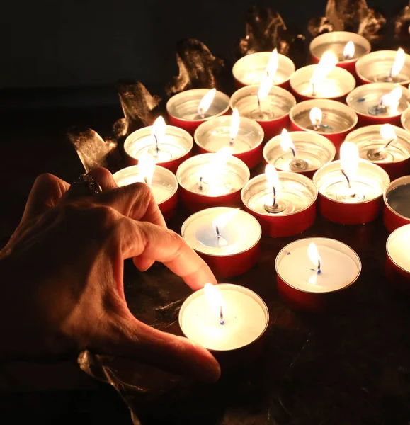 Hand van een vrouw en vele aangestoken kaarsen op de begraafplaats na de b — Stockfoto