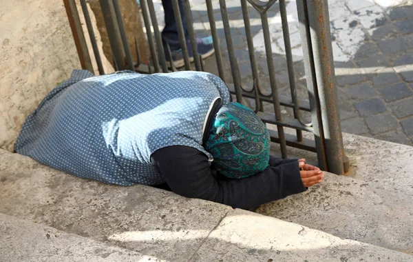 Elderly gypsy woman asking for alms kneeling on the ground with — Stock Photo, Image