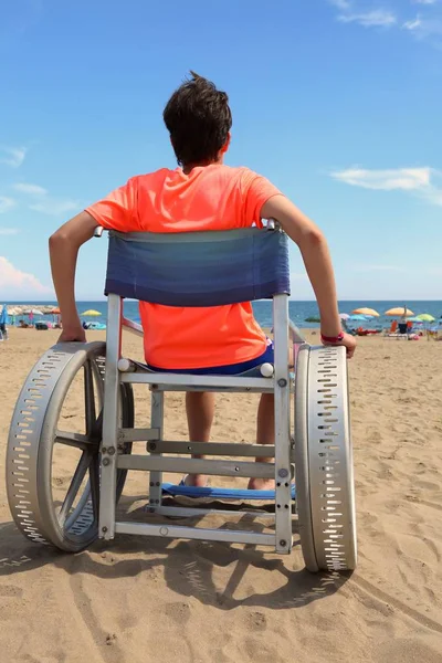 모래에 큰 바퀴를 가진 휠체어에 어린 아이 — 스톡 사진