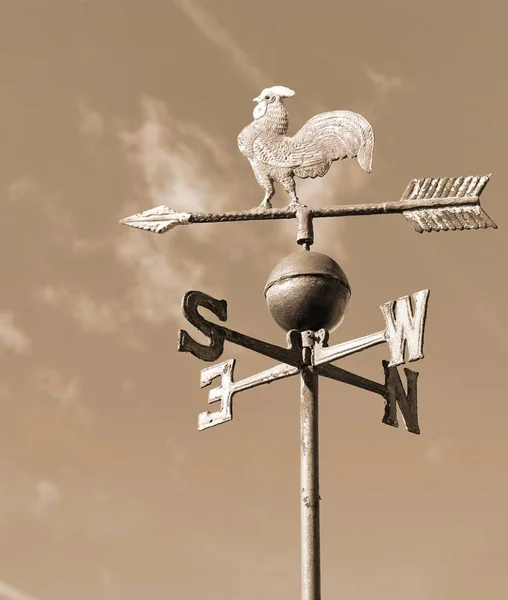 old wind vane with cock in iron in sepia toned