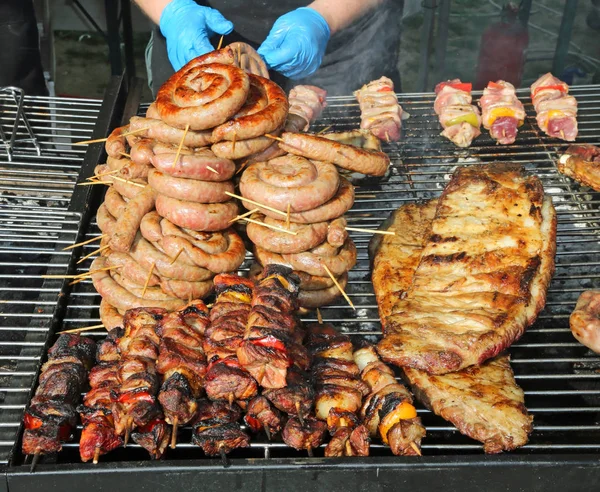 Koch mit blauen Handschuhen beim Kochen der Fleischspieße mit Paprika — Stockfoto