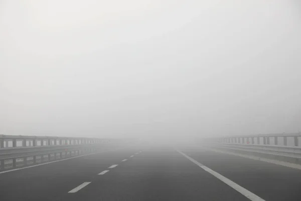 Шоссе с очень плотным опасным туманом без машин зимой — стоковое фото