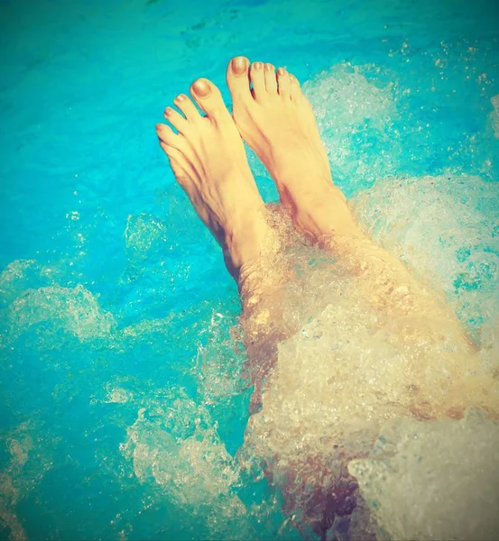 Jambes d'une jeune femme qui se détend dans le bain à remous du spa avec — Photo