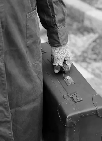 poor man with old leather suitcase and gloves  with black and wh