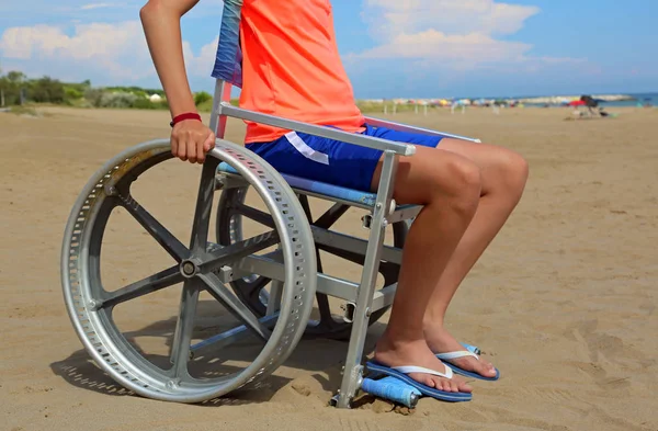 Kumlu plajda tekerlekli sandalyede çocuk — Stok fotoğraf