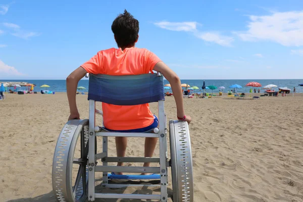 Młody chłopak na wózku inwalidzkim na plaży — Zdjęcie stockowe