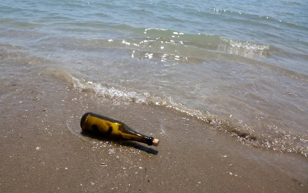 Бутылка с посланием, которое несут волны на берегу — стоковое фото