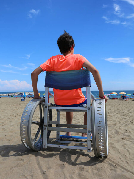 wheelchair with a young boy on the beach of the resort