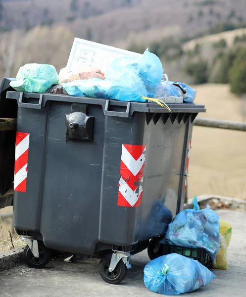Маленький черный мусорный бак и много мешков для мусора — стоковое фото