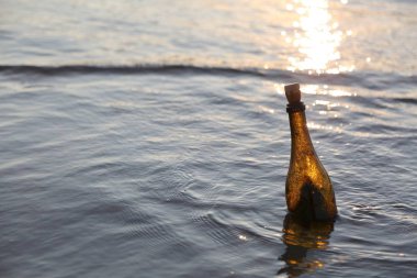 gün doğumunda su üzerinde cam şişesi
