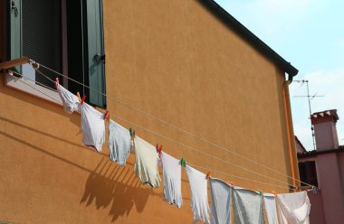 turuncu bir evin dışında kurumaya asılı giysiler