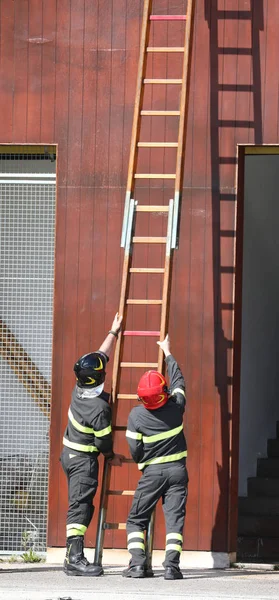 Ladder and two firefighter with helmet in the fire station — Stock Photo, Image