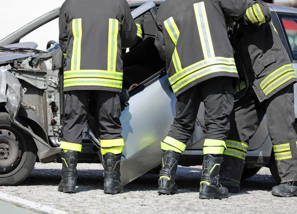 Itfaiyeciler kurtarmak için bir araba kazasından sonra bir arabanın kapısını kaldırmak — Stok fotoğraf