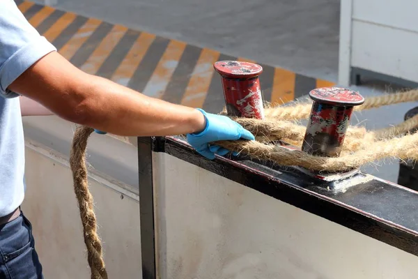 Sailor ties a hemp rope to the dock to facilitate the mooring — Stock Photo, Image