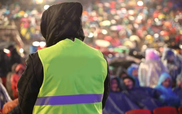 Boy with high visibility jacket and many people at stadium befor — Stock Photo, Image