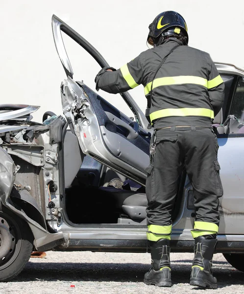Brandweerman verwijdert de deur van een vernietigde auto na een auto-ongeluk — Stockfoto