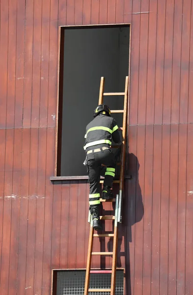 Bombeiro no quartel de bombeiros com madeira a escada — Fotografia de Stock