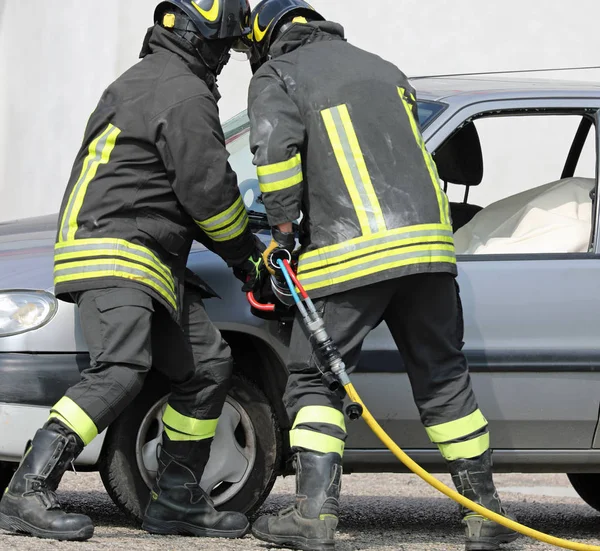 Bomberos y un auto roto en el accidente —  Fotos de Stock