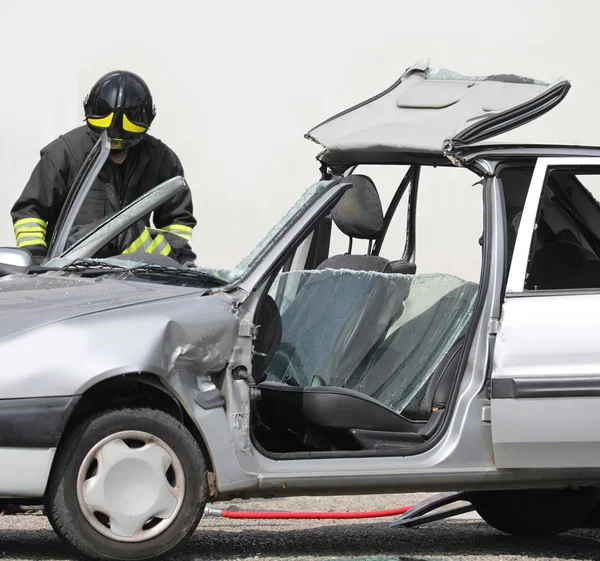 Brandweerman en een gebroken auto op de weg — Stockfoto