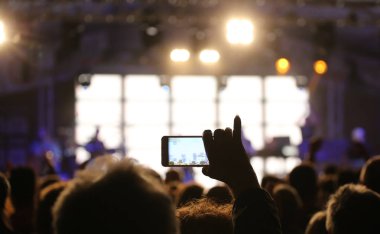 kişi akıllı telefon ile konserin bir video kaydeder