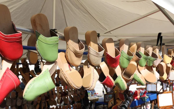 Many wooden clogs hanging from a market stall — Stock Photo, Image