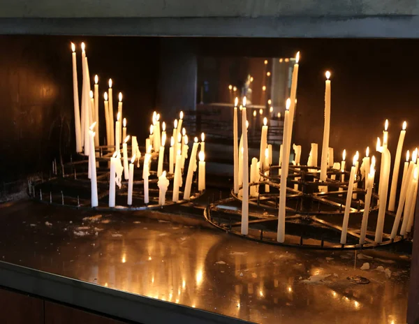 Muitas velas votivas acesas pelos fiéis na igreja — Fotografia de Stock