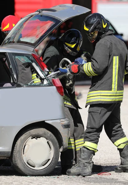 Пожежники з великими ножицями, щоб відкрити зламану машину — стокове фото
