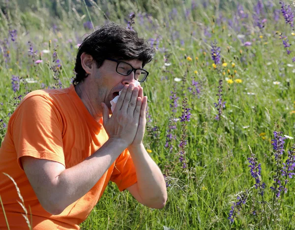 Young boy with orange shirt sneezes because of allergy on the la — Stock Photo, Image