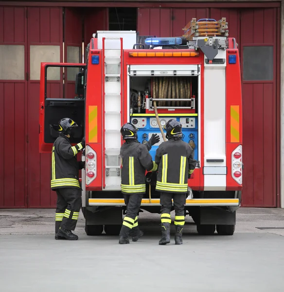 Firefighters in action and the fire engine during a fire drill — Stock Photo, Image