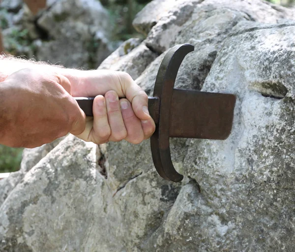 Mãos e a espada mágica na pedra — Fotografia de Stock