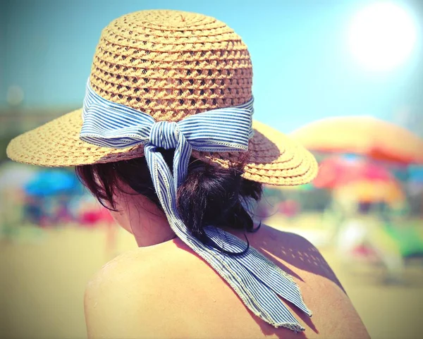 Frau mit Strohhut am Strand mit Sonnenschirmen beim Sonnenbräunen — Stockfoto