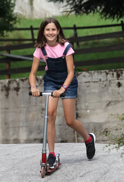 Маленькая девочка улыбается белый играет со скутером — стоковое фото
