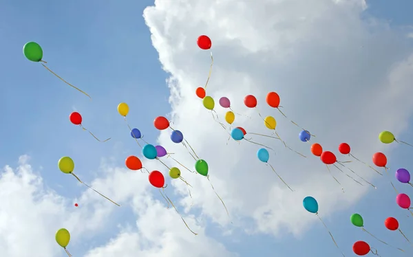 Dozen of colored balloons in the sky with many white clouds symb — Stock Photo, Image