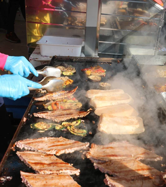 Cozinhe com luvas de látex enquanto cozinha comida e salsicha no quente — Fotografia de Stock